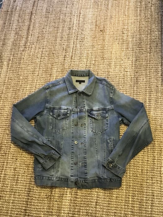 Original phone photo of a denim jacket on a woven rug